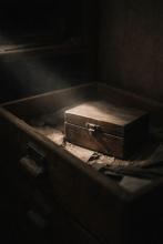 Ein Koffer im Dunkeln, ein Lichtstrahl fällt darauf