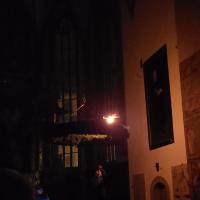 In der dunklen Kirche wird der große hängende Adventskranz entzündet